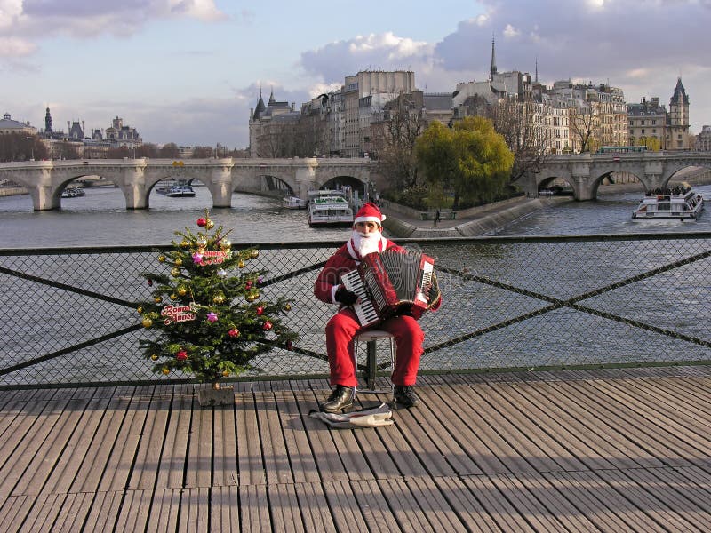 A young man dressed as Pere Noel plays the accordion on the Pont des Arts in Paris