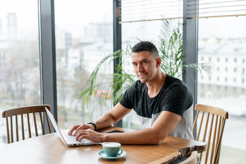 Freelancer Work on Netbook in Modern Coworking. Young Man Drinking