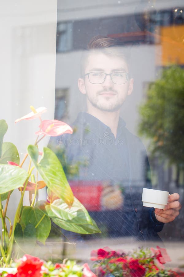 Young man drinking his morning coffee. Photo behind glass stock image Young man drinking his morning coffee. Photo behind glass stock image
