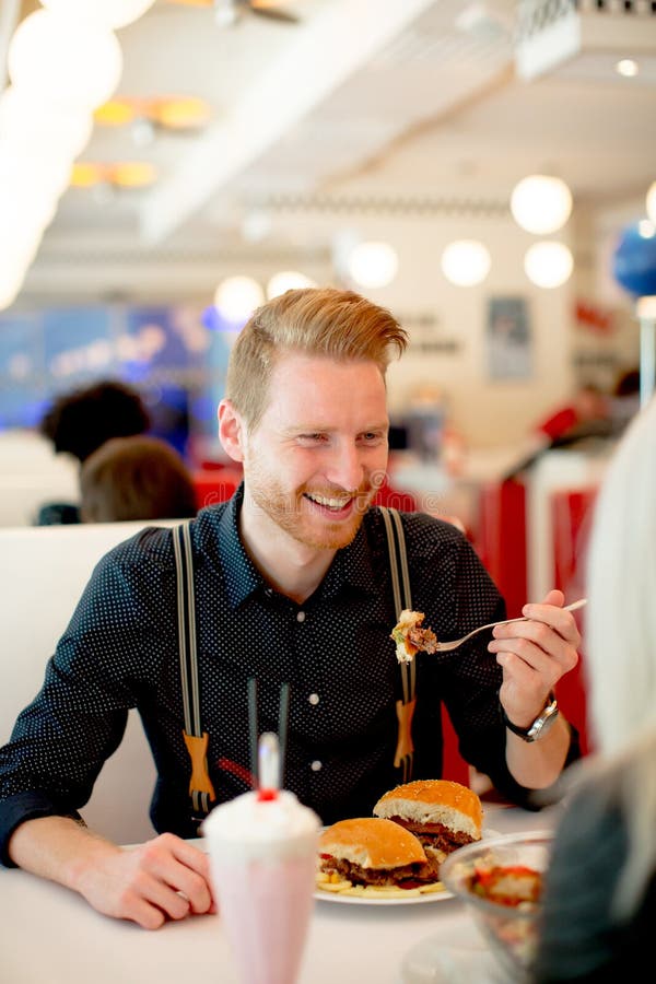Young Man Eating Cheeseburger in Diner Stock Image Image of unhealthy