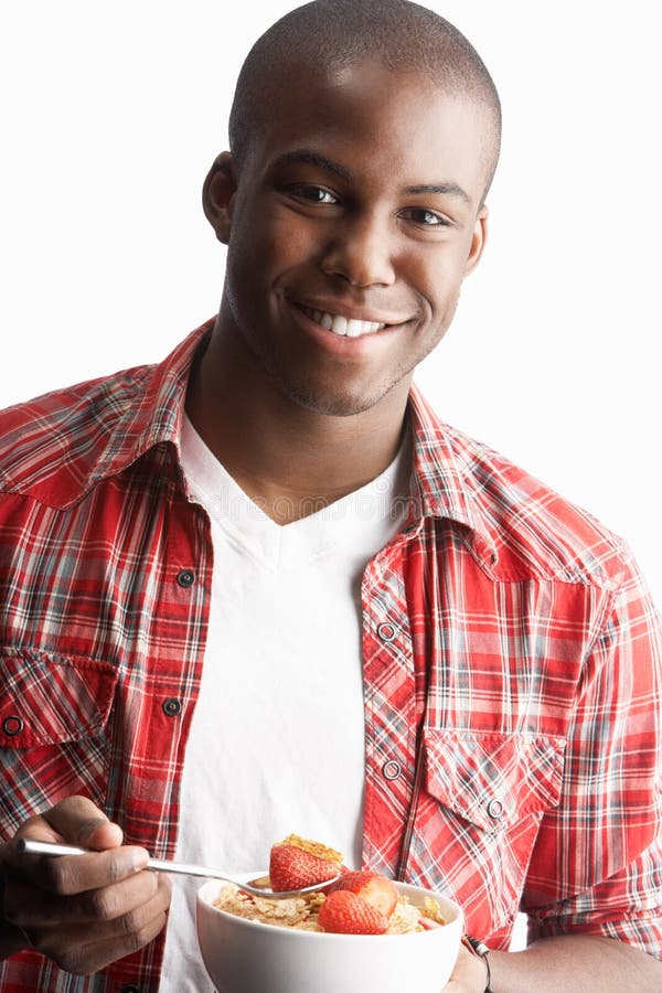 Young Man Eating Bowl Of Cereal In Studio