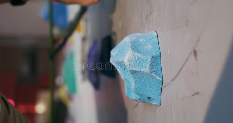 A young man climbs up the artificial surface of the climbing wall stock footage