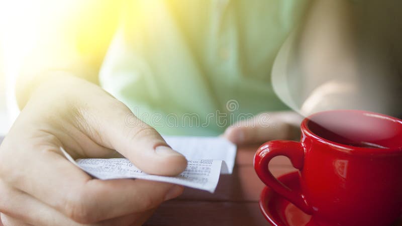 A young man examines the bill in a cafe on a Sunny summer morning stock photos A young man examines the bill in a cafe on a Sunny summer morning stock photos