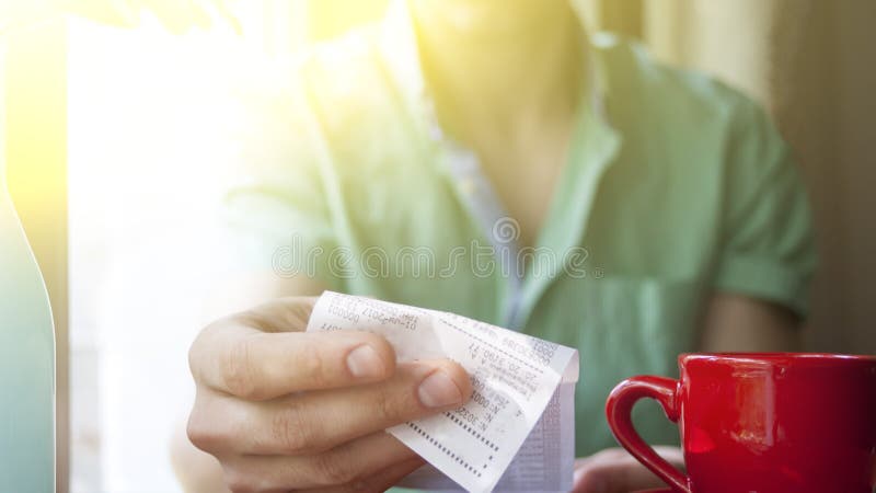 A young man examines the bill in a cafe on a Sunny summer morning stock image A young man examines the bill in a cafe on a Sunny summer morning stock image