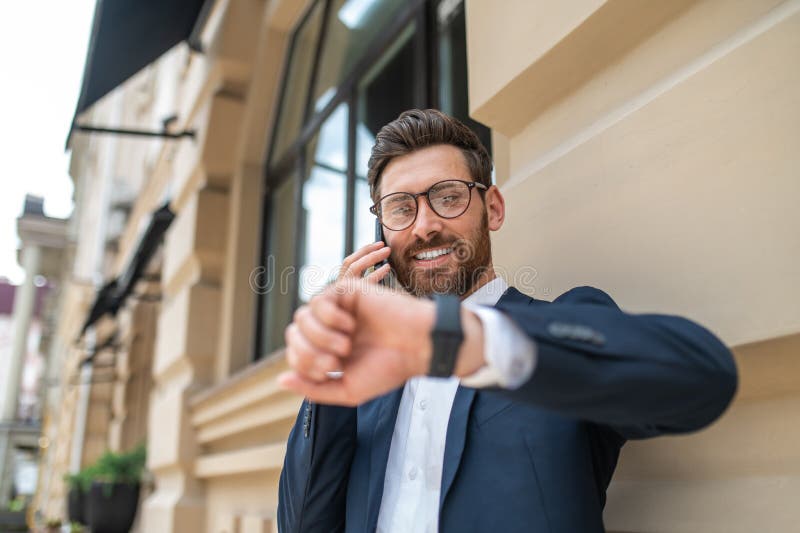Young Man in Eyeglasses Waiting for Someone and Looking at His Watch