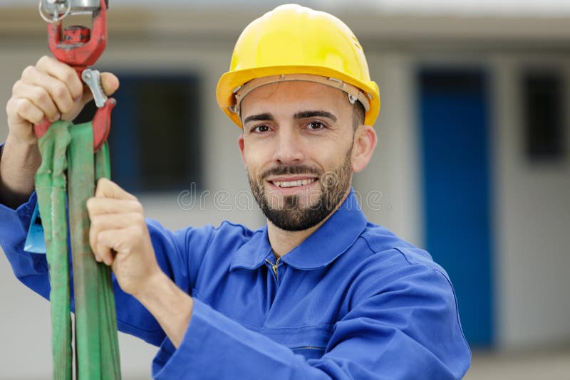 Young man in factory preparing straps for lifting hoist