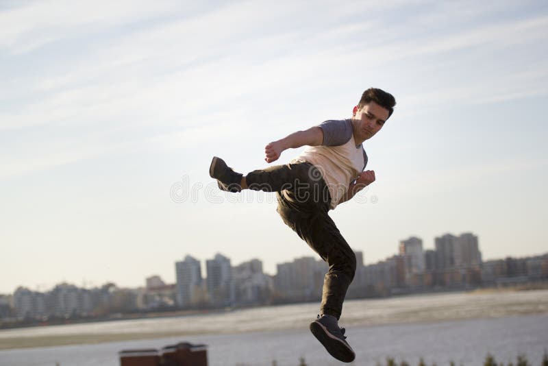 Young male kick fighter performs acrobatic kick in front of skyline stock photo Young male kick fighter performs acrobatic kick in front of skyline stock photo