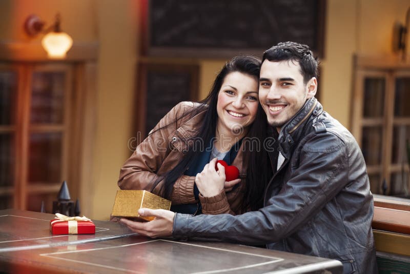 The young man gives a gift to a young girl in the cafe and they