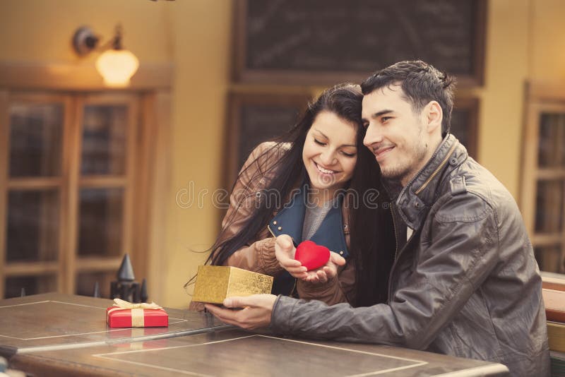 The young man gives a gift to a young girl in the cafe and they