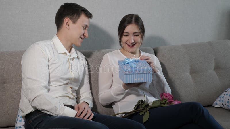 Young man giving Valentine gift box and bouquet of red roses to his girlfriend