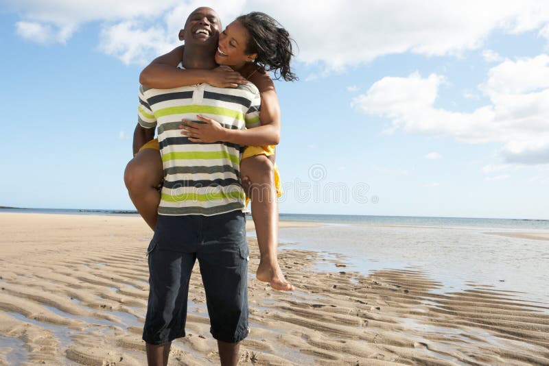 Young Man Giving Woman Piggyback Along Shoreline