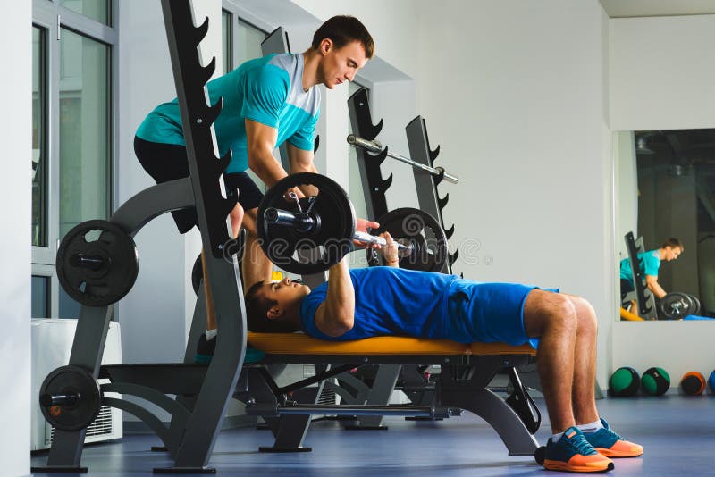 Young Man in Gym Exercising Chest on the Bench Press with Barbell Stock