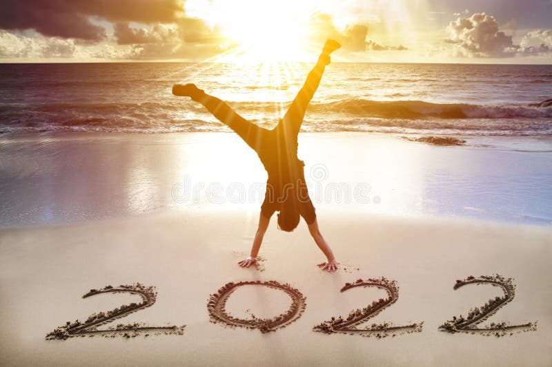 Young man handstand on the beach.  happy new year 2022 concept.  stock photos