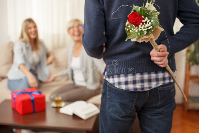 Young man holding bouquet of flowers behind the back for his mother stock photos Young man holding bouquet of flowers behind the back for his mother stock photos