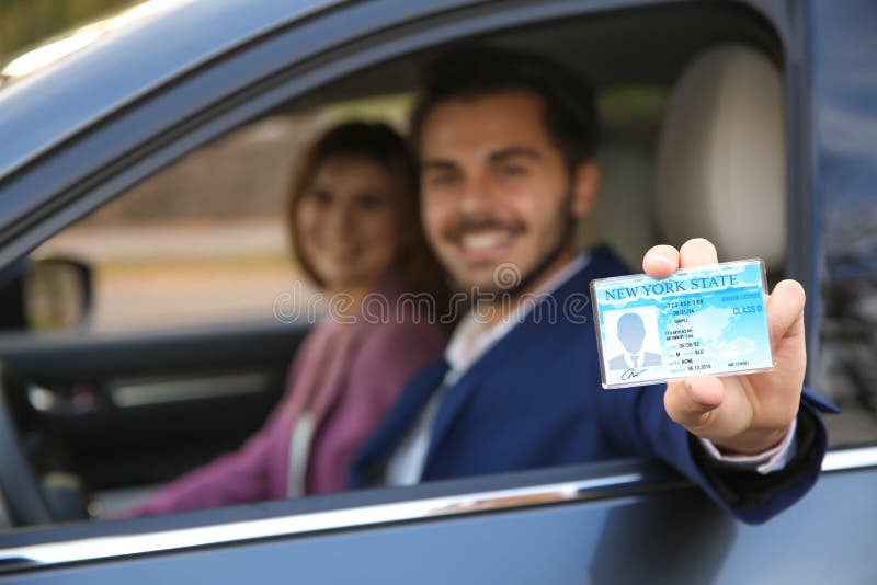 Young Man Holding Driving License in Car with Passenger Stock Image