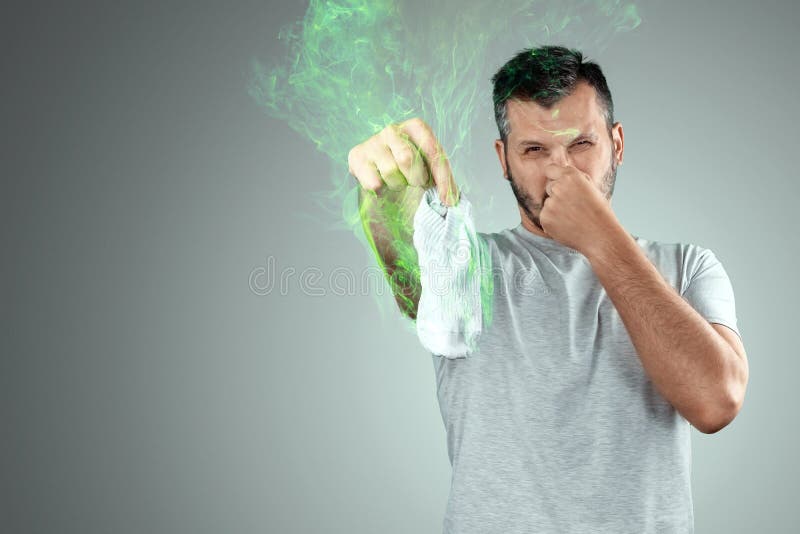 A Young Man Holds His Smelly Socks and Covers His Nose with His