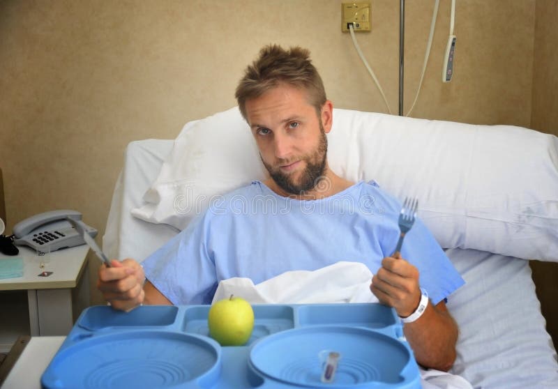 Young man in hospital room after suffering accident eating healthy apple diet clinic food moody and sad royalty free stock images Young man in hospital room after suffering accident eating healthy apple diet clinic food moody and sad royalty free stock images