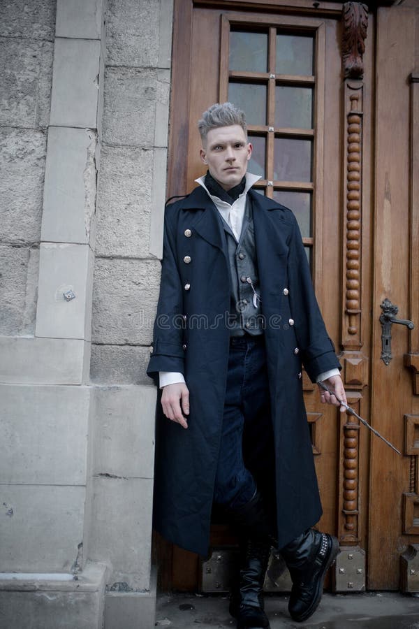 Young man in image of black magician walks on street with magic wand royalty free stock photos Young man in image of black magician walks on street with magic wand royalty free stock photos