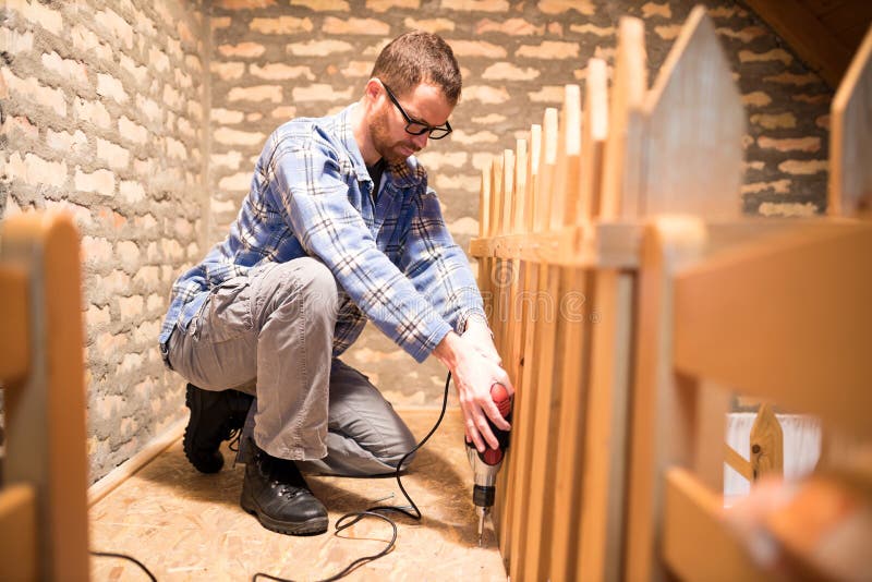 Young Man Installing Chipboard Flooring In The Attic Stock Photo