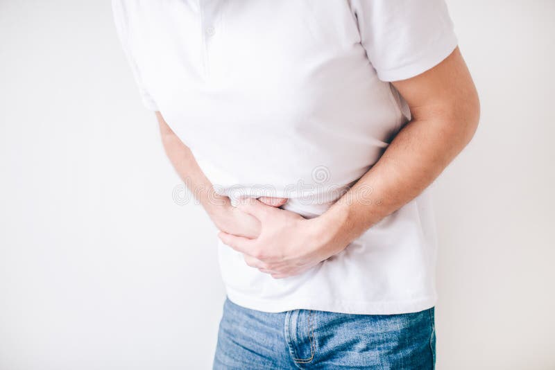 Young man isolated over white background. Cut view of guy holding hands over stomach because of diarrhea. Painful and aching