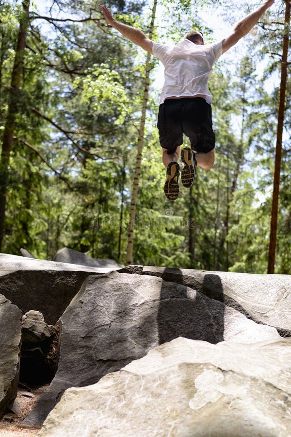 Young man jumps on a rock in a coniferous forest. Active extreme tourism stock photo Young man jumps on a rock in a coniferous forest. Active extreme tourism stock photo