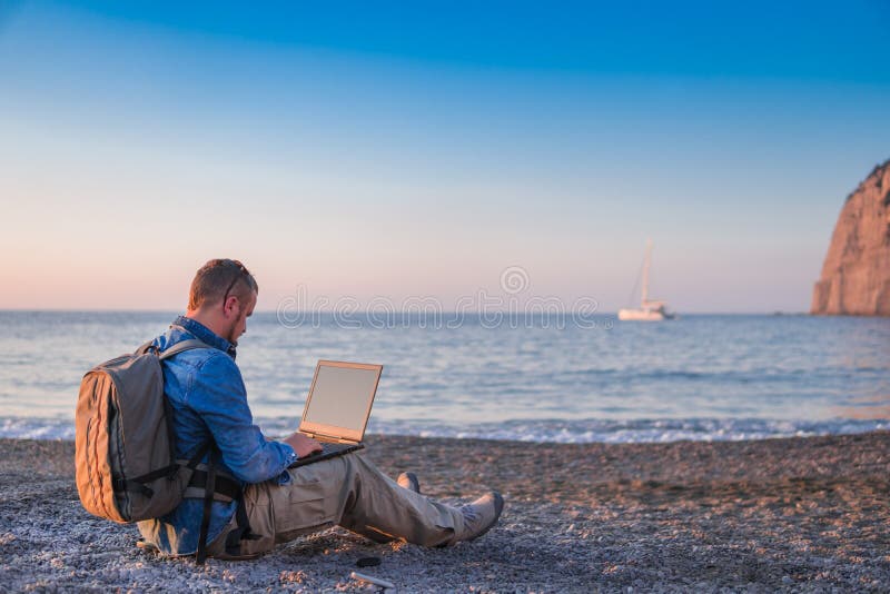 Young man with laptop working on the beach. Freedom, remote work, freelancer, technology, internet, travel and vacation concepts stock photo Young man with laptop working on the beach. Freedom, remote work, freelancer, technology, internet, travel and vacation concepts stock photo