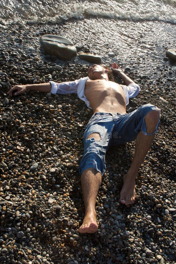 Young man lies on coastline