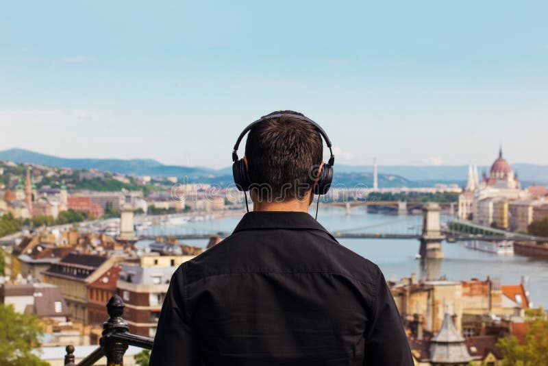 Young man listening music back view with Budapest