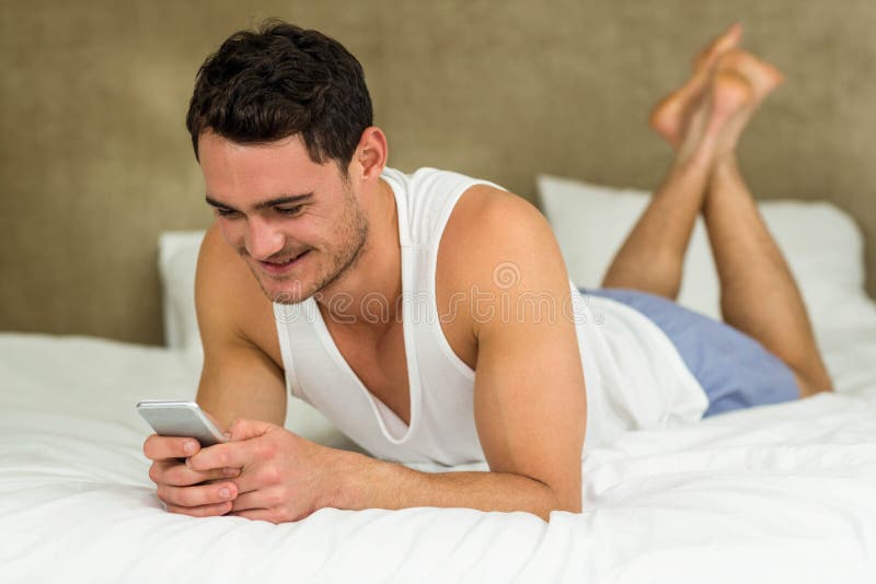 young-man-lying-bed-his-phone-texting-smiling-66932153.jpg