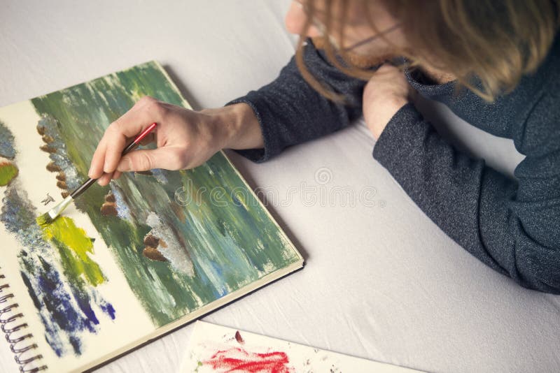 Young man lying in bed painting a picture royalty free stock image Young man lying in bed painting a picture royalty free stock image