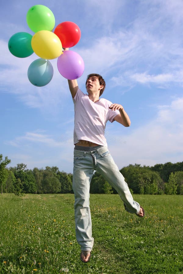 Young man with many colored balloons jumping
