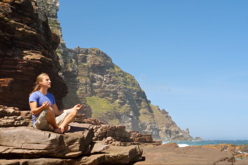 Young man meditates against sea-misty mountain