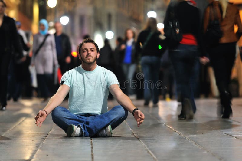 Mladý muž jóga meditace v lotosové pozici na ulici v noci.