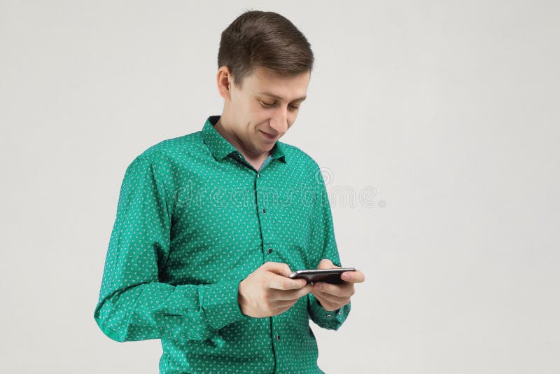 Young man with mobile phone in his hands is isolated on light background stock images Young man with mobile phone in his hands is isolated on light background stock images