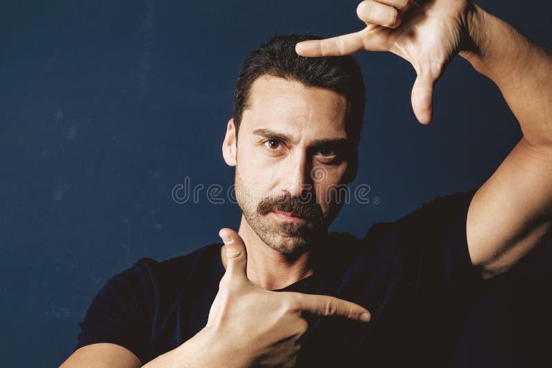 Young man with moustache framing his face with his hands
