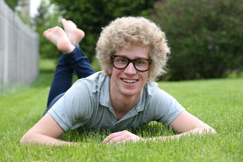 Blonde teen boy with oversize glasses and crazy blond hair in grass. Blonde teen boy with oversize glasses and crazy blond hair in grass