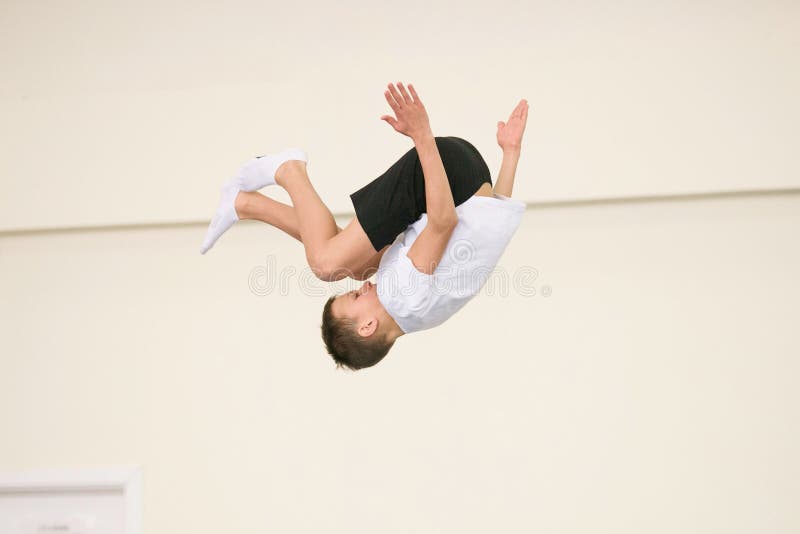 The Young Man Performs Gymnastic Exercises in the Gym. Stock Photo
