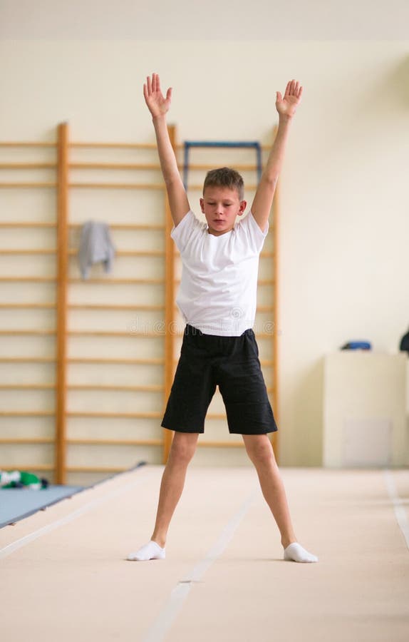 The Young Man Performs Gymnastic Exercises in the Gym. Stock Photo