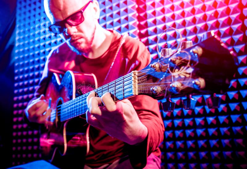 Young man playing on the acoustic guitar in sound recording studio. stock photos