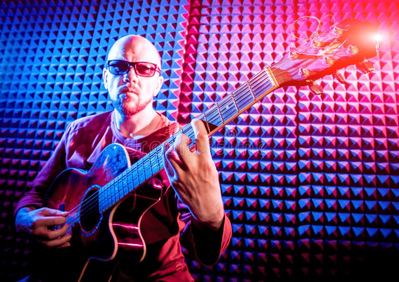 Young man playing on the acoustic guitar in sound recording studio. royalty free stock photo