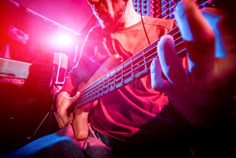 Young man playing on the bass guitar in sound recording studio. stock image