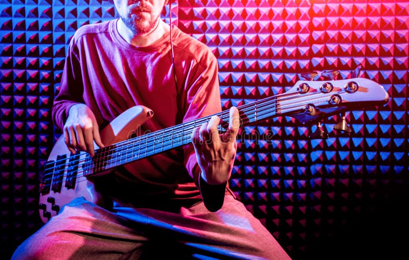 Young man playing on the bass guitar in sound recording studio. stock images