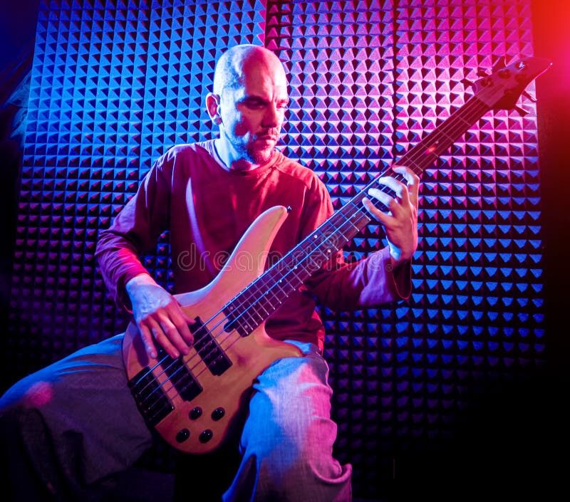 Young man playing on the bass guitar in sound recording studio. royalty free stock photos