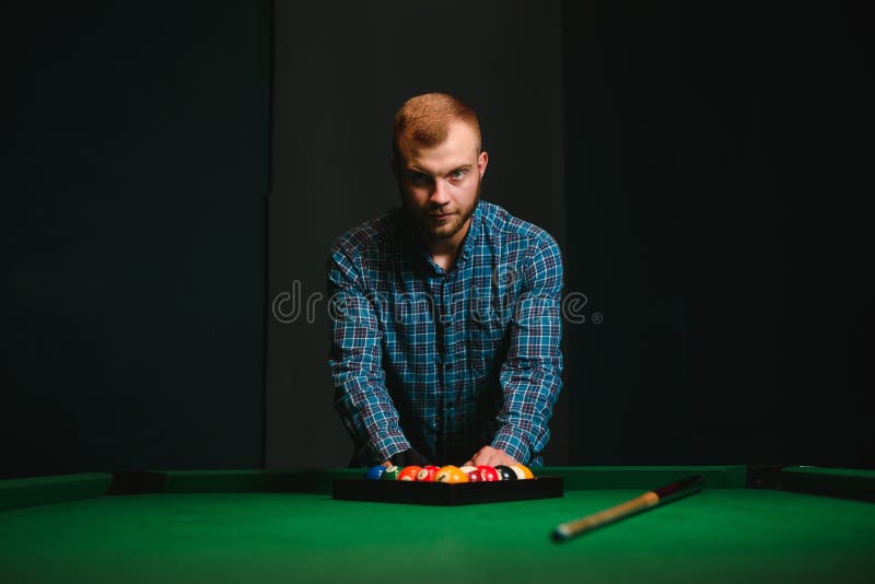 Young Man Playing Billiards in the Dark Billiard Club Stock Image