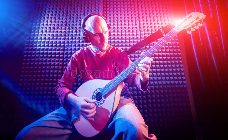 Young man playing on the bouzouki in sound recording studio. royalty free stock photography