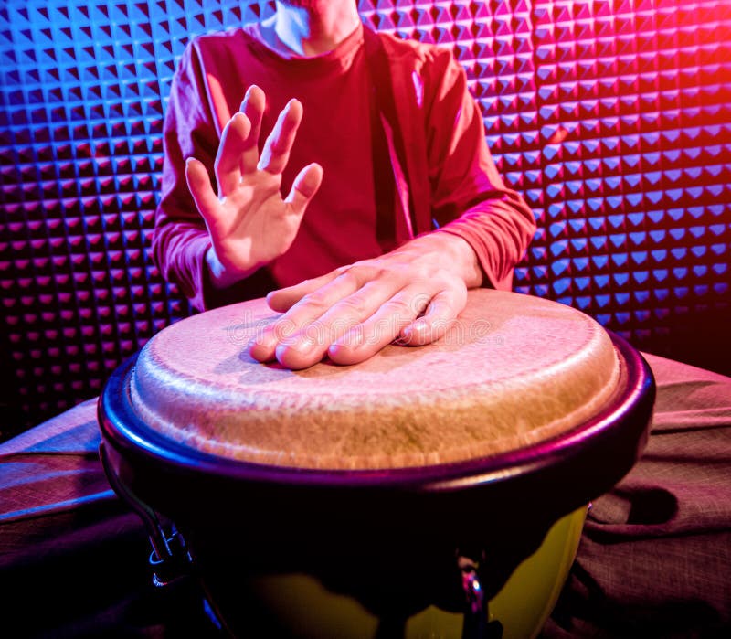 Young man playing on djembe in sound recording studio. royalty free stock images