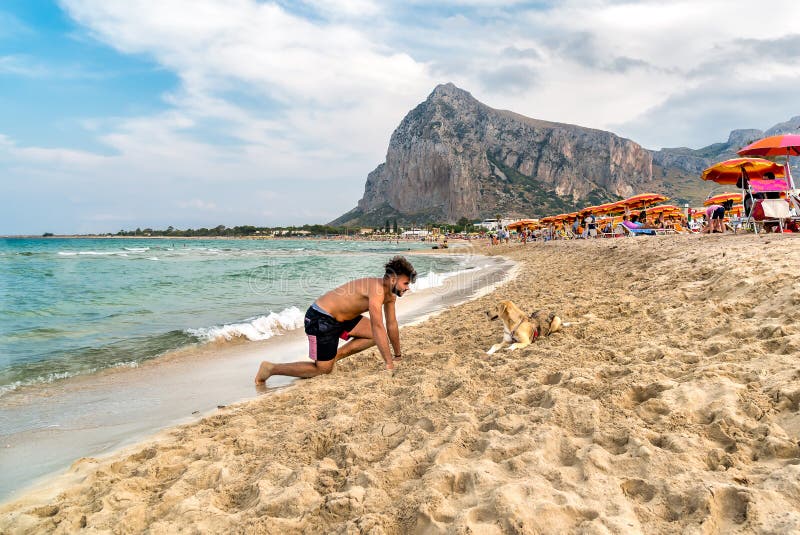 Young Man Playing with a Dog on the San Vito Lo Capo Beach on a Cloudy Day.  Editorial Photography - Image of holiday, seascape: 89196852