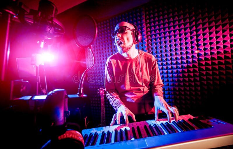Young man playing piano in sound recording studio. stock photo