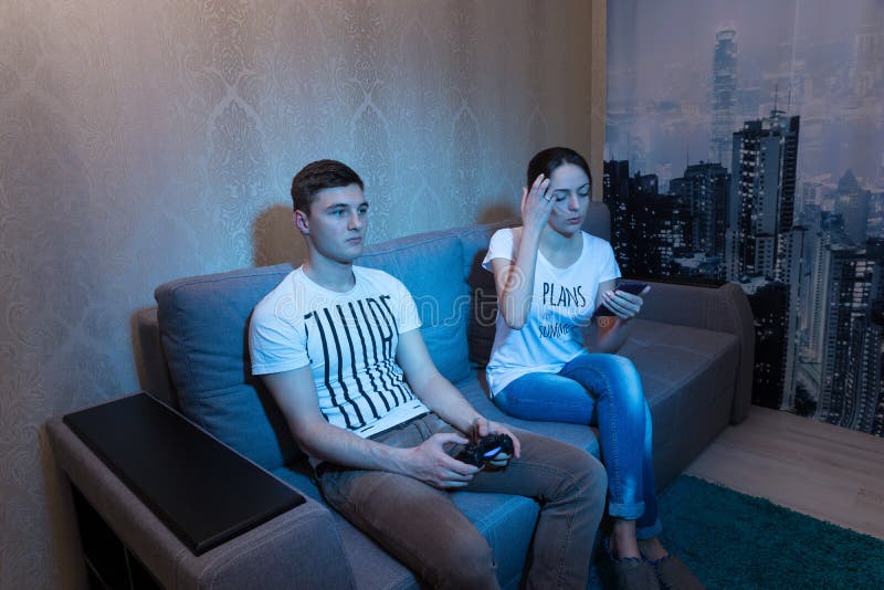 Man Playing Video Games At Home And His Girlfriend Bored Beside Looking At  Him Stock Photo, Picture and Royalty Free Image. Image 52407663.