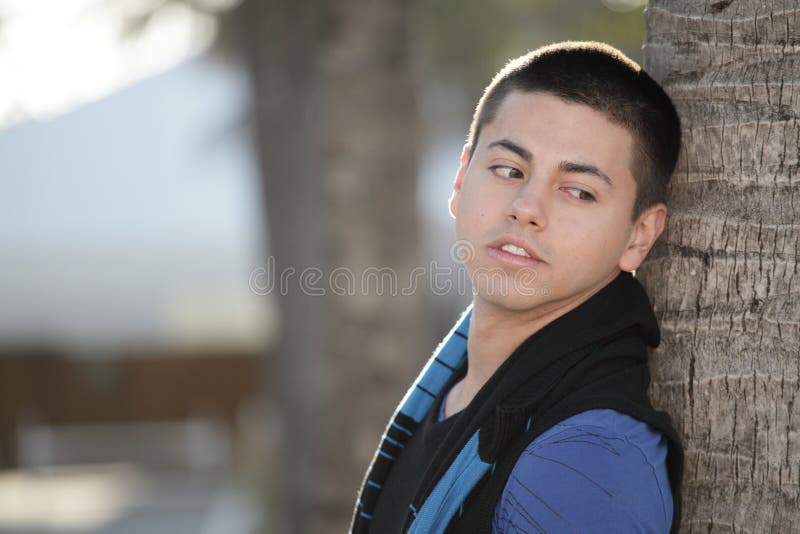 Young man posing by a palm tree